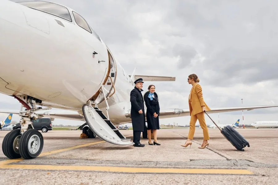 Passengers walking across the ramp to a private jet with the crew
