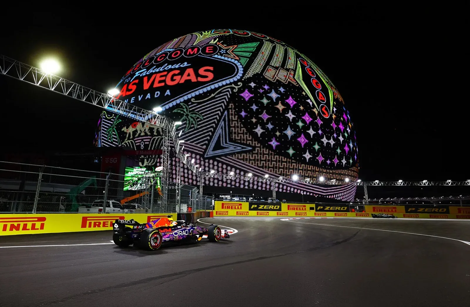 Formula 1 car passing the Sphere on the floodlit Las Vegas street circuit at night